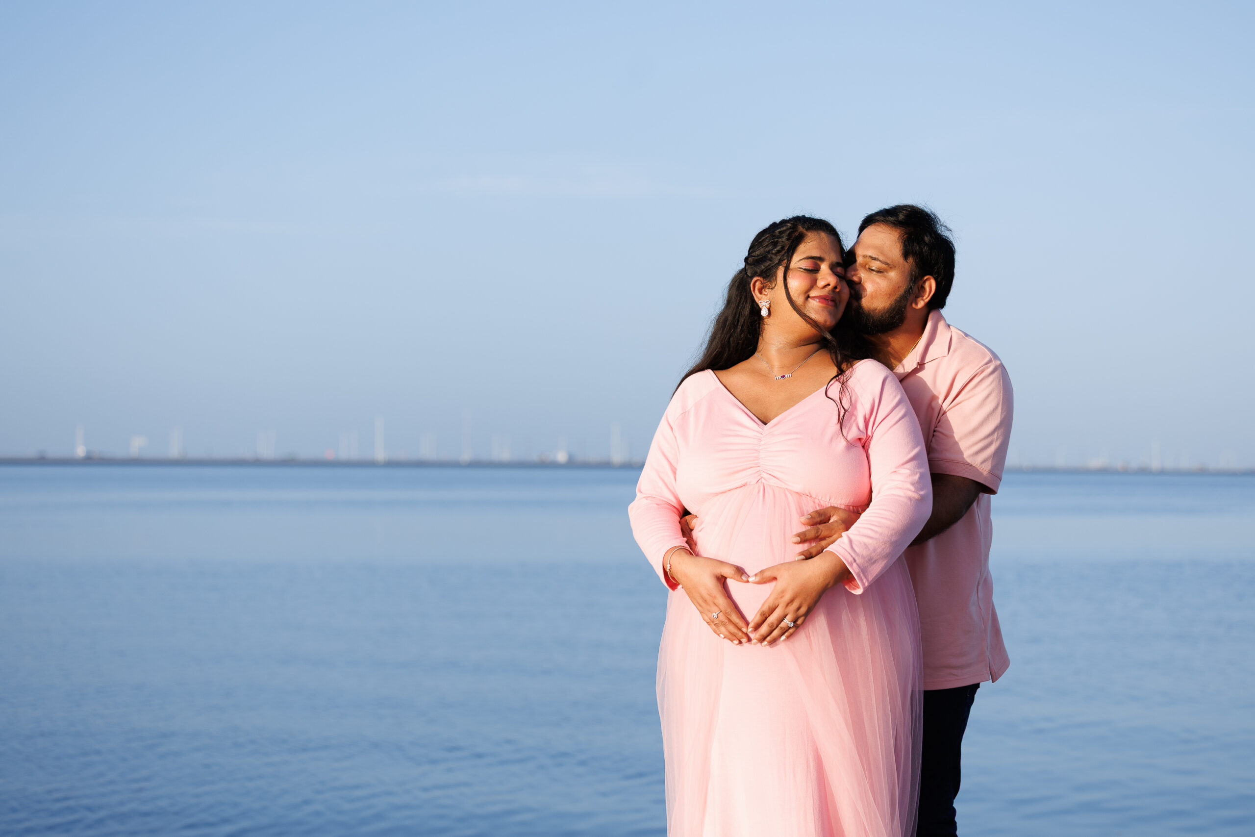 LO1A4909 A close-up of a bride and groom holding hands, showcasing their wedding bands and elegant attire against a softly lit background.